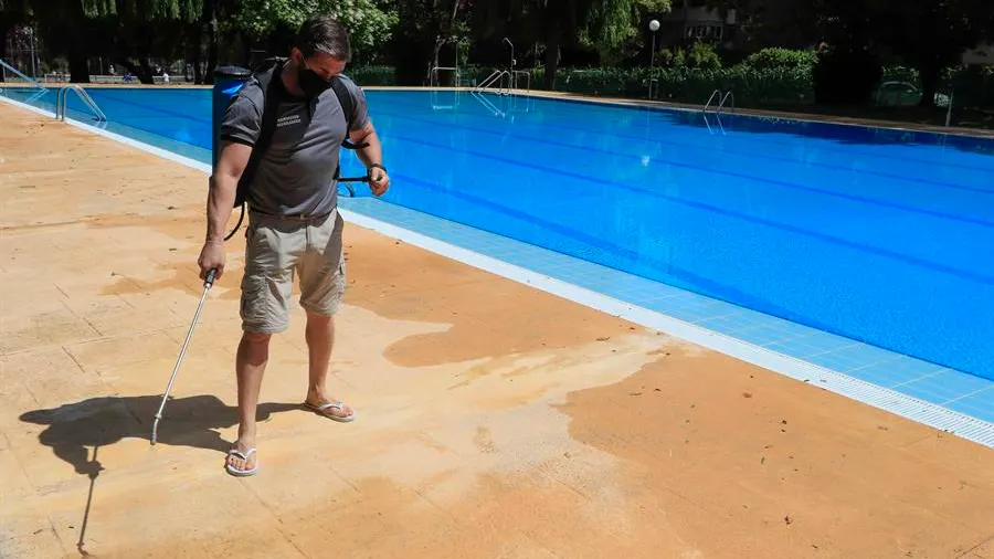 Un operario desinfecta el perímetro de una piscina.