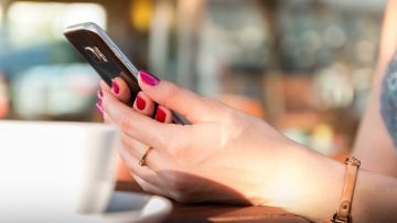 Imagen de una mujer usando un teléfono móvil en un bar