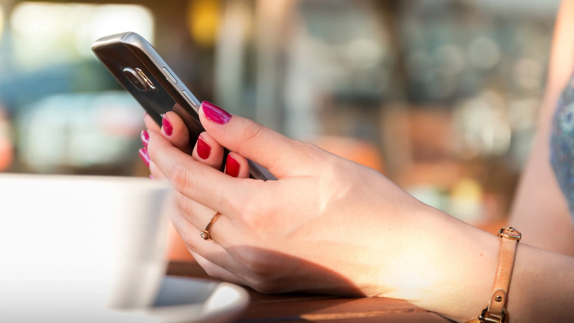 Imagen de una mujer usando un teléfono móvil en un bar