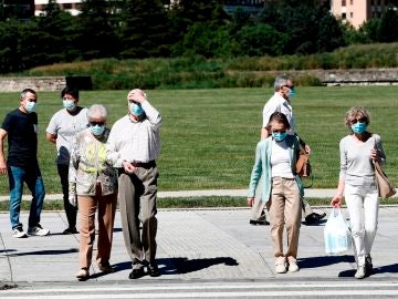 Un grupo de personas con mascarilla pasean por un parque Un grupo de personas con mascarilla pasean por un parque