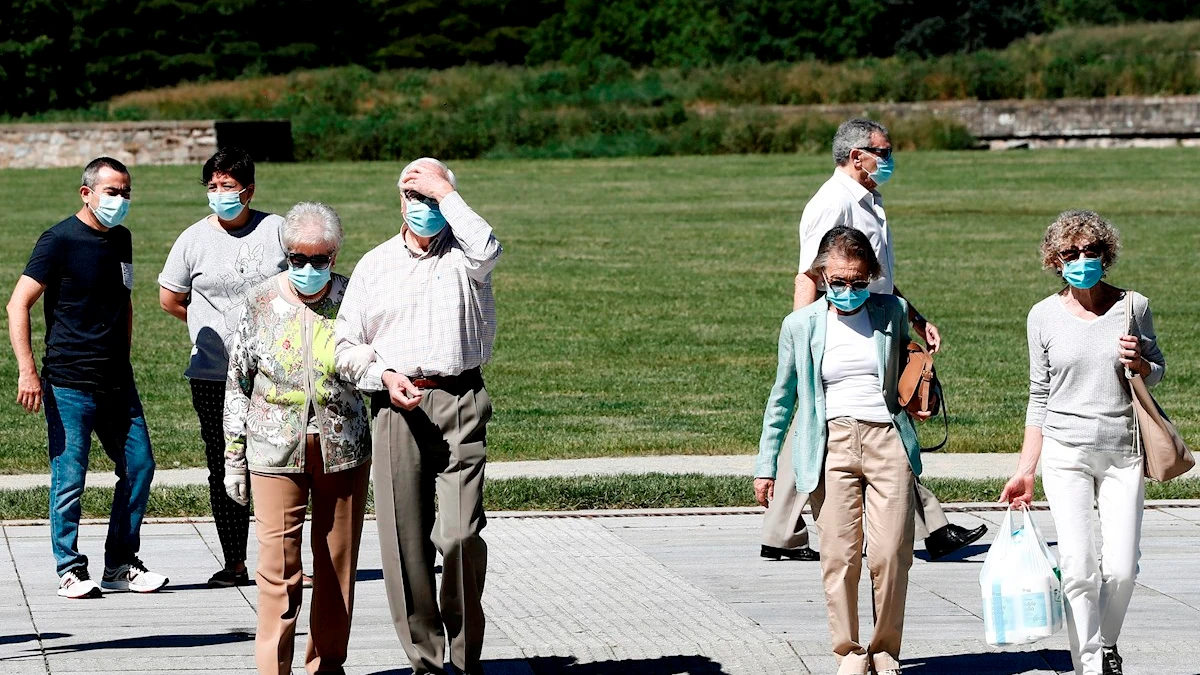 Un grupo de personas con mascarilla pasean por un parque