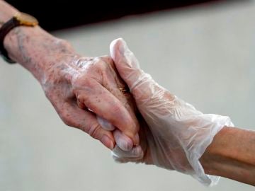 Una sanitaria da la mano a una anciana en una residencia Una sanitaria da la mano a una anciana en una residencia