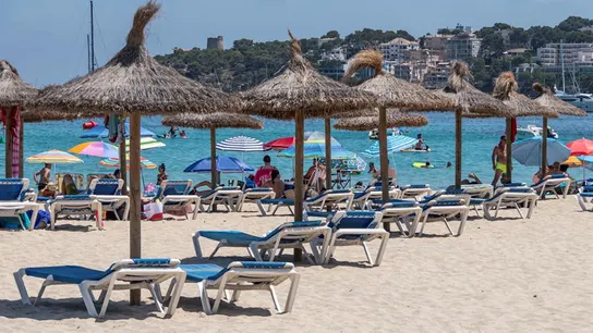 Imagen de unas sombrillas y hamacas vacías en la arena en una playa Imagen de unas sombrillas y hamacas vacías en la arena en una playa