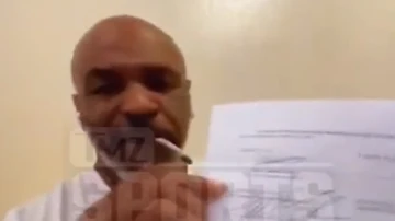 Mike Tyson muestra el contrato de su vuelta al ring mientras se fuma un porro