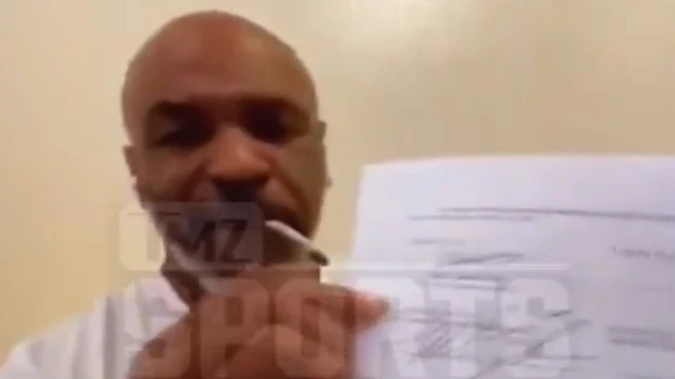 Mike Tyson muestra el contrato de su vuelta al ring mientras se fuma un porro