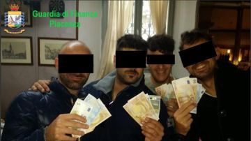 Imagen facilitada por la Guardia de Finanzas de cuatro de los carabineros arrestados mostrando dinero. 