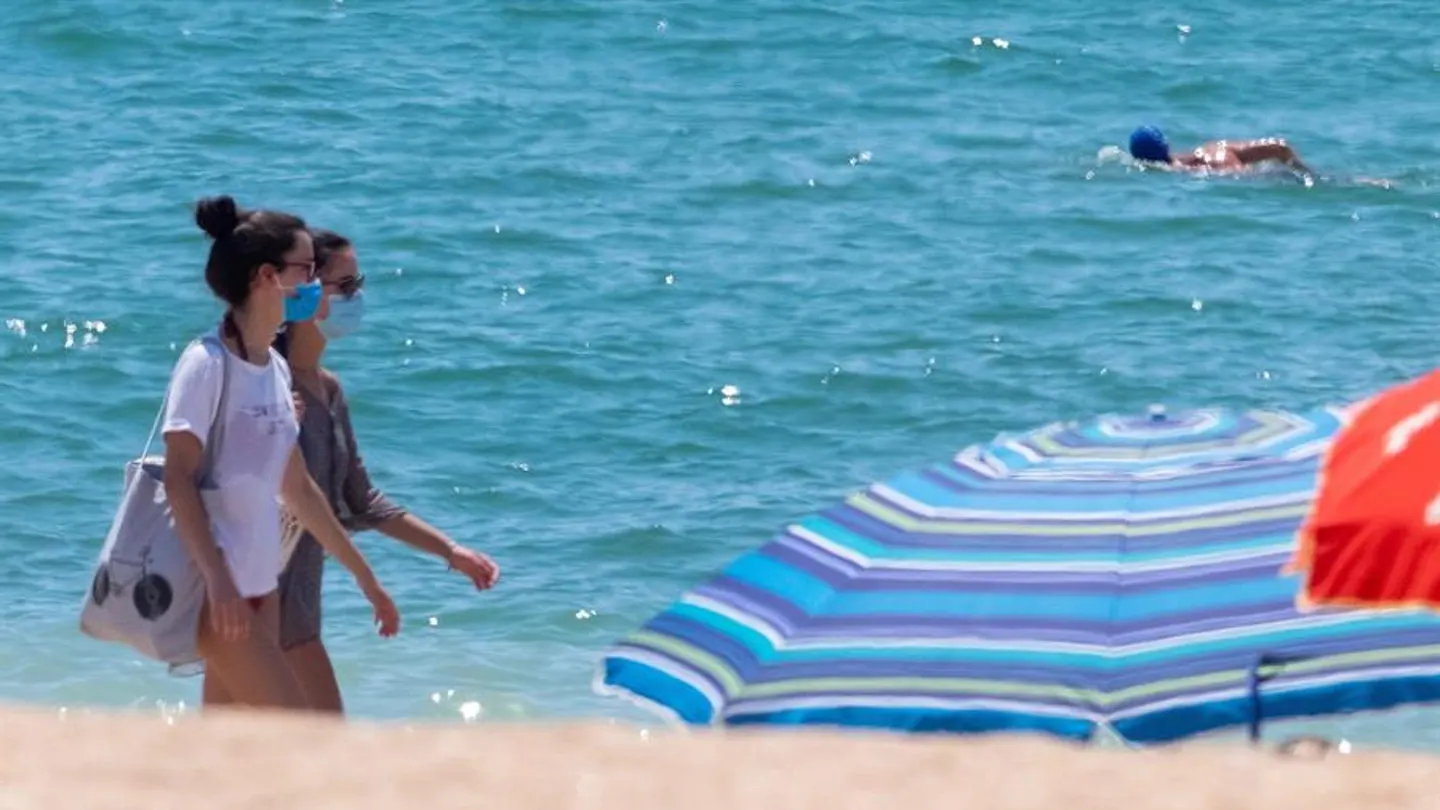 Dos jóvenes con mascarilla en una playa de Andalucía Dos jóvenes con mascarilla, obligatoria en las playas de Andalucía