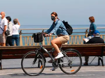 Una mujer pasea en bicicleta protegida con una mascarilla por el paseo de la Zurriola de San Sebastián Una mujer pasea en bicicleta protegida con una mascarilla por el paseo de la Zurriola de San Sebastián