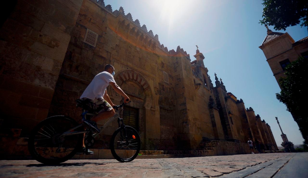 Un hombre hace turismo en bicicleta pasa junto la Mezquita-Catedral en Córdoba