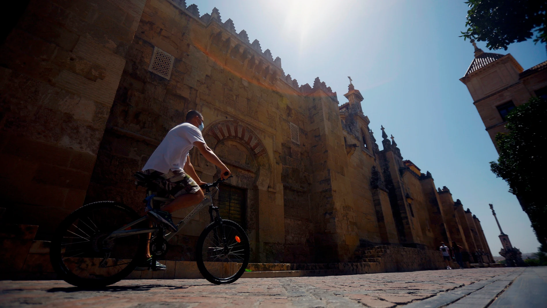 Un hombre hace turismo en bicicleta pasa junto la Mezquita-Catedral en Córdoba