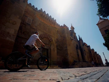Un hombre hace turismo en bicicleta pasa junto la Mezquita-Catedral en Córdoba