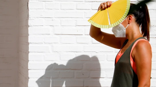 Una mujer se protege del sol con un abanico Una mujer se protege del sol con un abanico