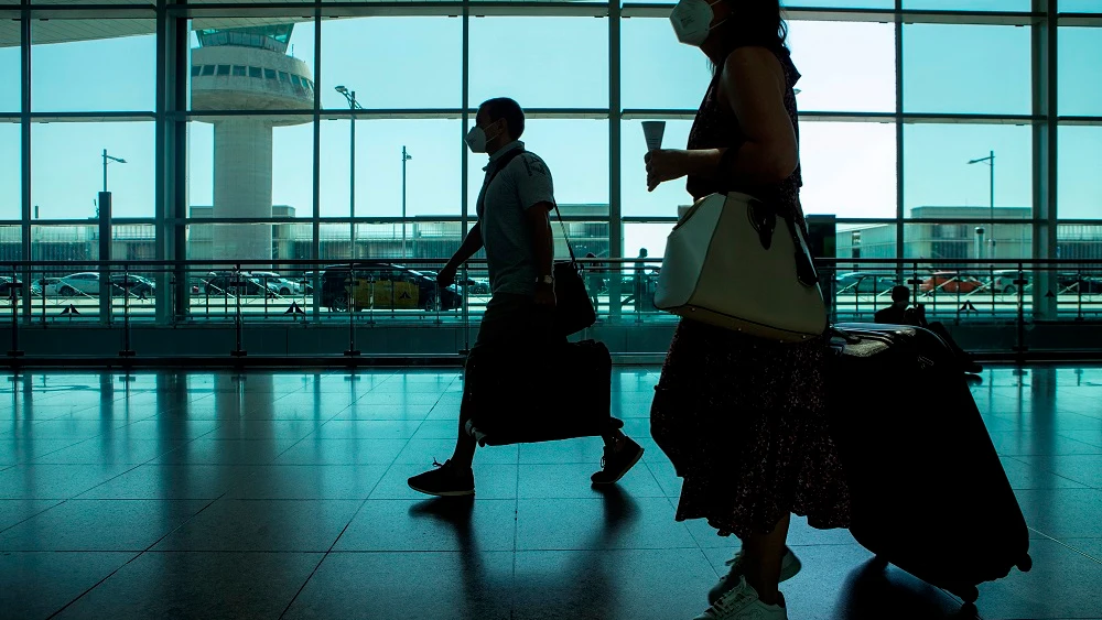 Viajeros con mascarillas caminan por el aeropuerto de El Prat