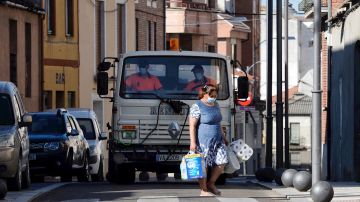  Una mujer pasa por delante de un camión que realiza tareas de desinfección por las calles de Íscar