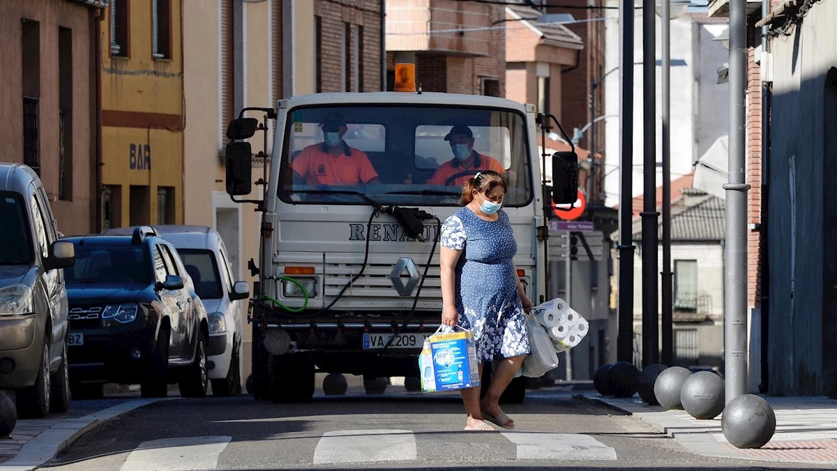  Una mujer pasa por delante de un camión que realiza tareas de desinfección por las calles de Íscar