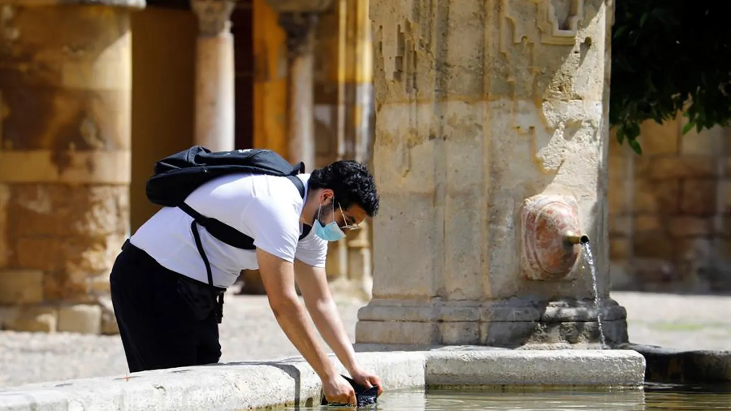 Un hombre se refresca en una fuente de Córdoba Un hombre se refresca en una fuente de Córdoba