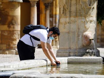 Un hombre se refresca en una fuente de Córdoba Un hombre se refresca en una fuente de Córdoba