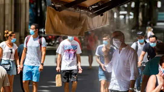 Personas paseando por Sevilla Viandantes del centro de Sevilla se paran bajo los atomizadores de agua de los negocios de hostelería