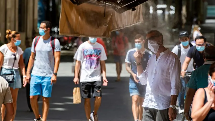 Viandantes del centro de Sevilla se paran bajo los atomizadores de agua de los negocios de hostelería