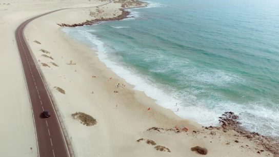 Un coche recorre una carretera a pie de playa en Fuerteventura Coches GLP: una alternativa barata y sostenible para recorrer España