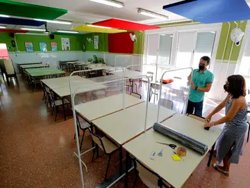 Dos docentes colocan los separadores en el comedor de un colegio
