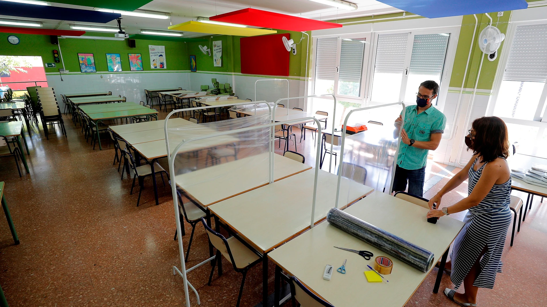 Dos docentes colocan los separadores en el comedor de un colegio