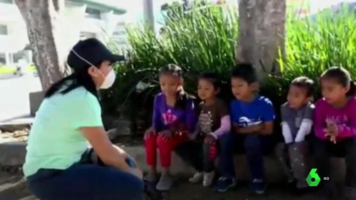 Imagen de una maestra dando clase en la calle a niños sin recursos de México