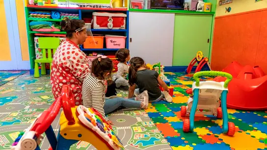 Vuelta al cole Una maestra con una pantalla protectora en un aula de Infantil con varios niños