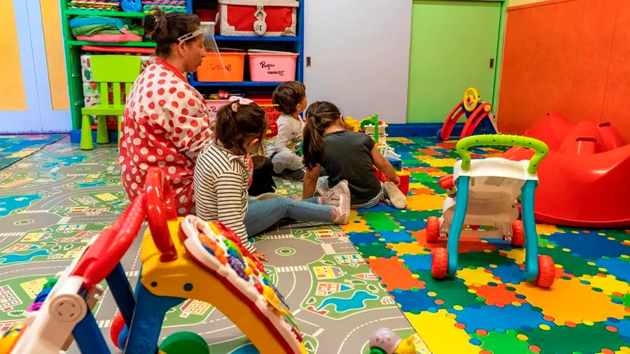 Una maestra con una pantalla protectora en un aula de Infantil con varios niños