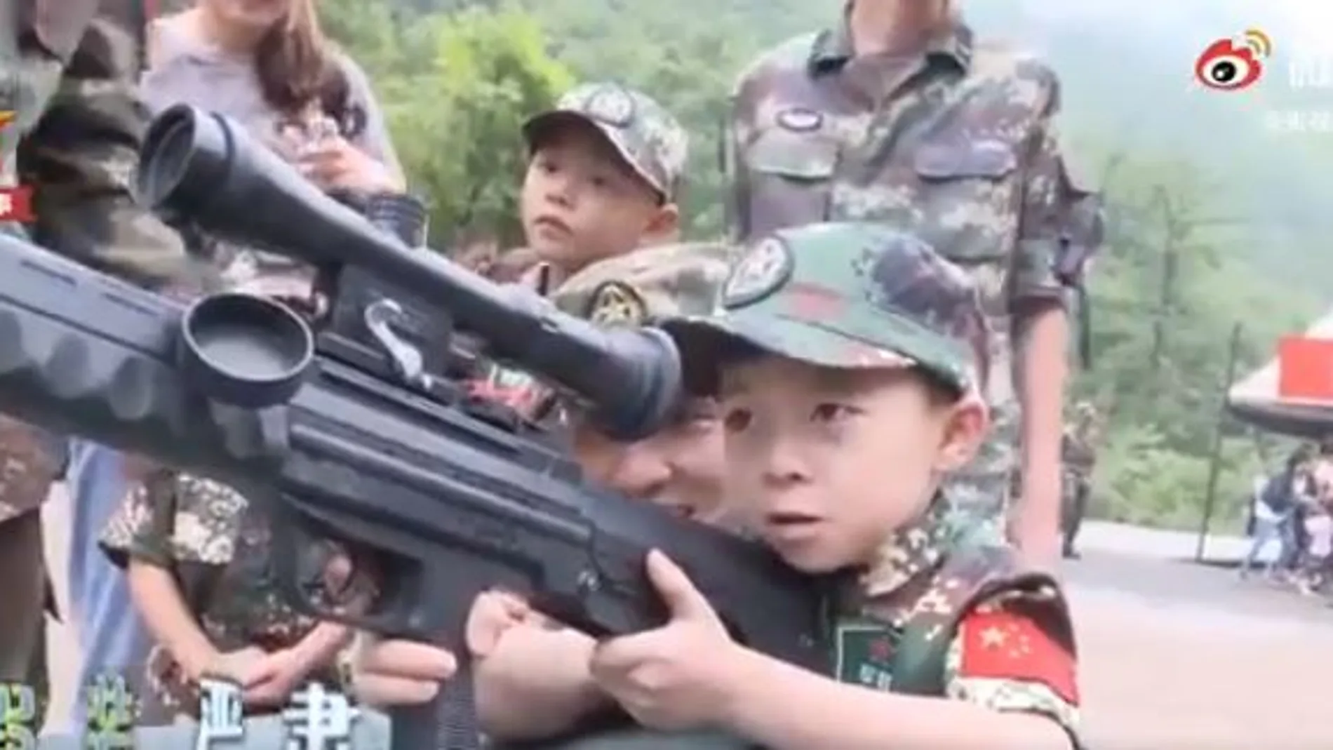 Un niño chino sostiene un arma durante una visita a un centro de entrenamiento militar