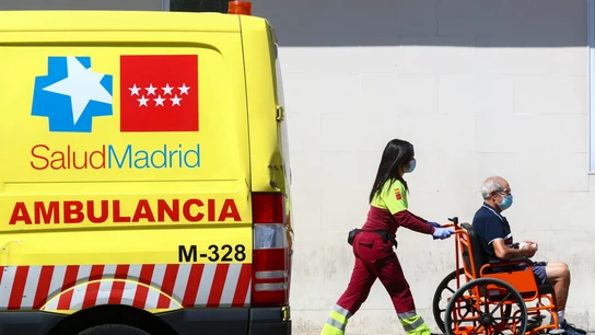 Una sanitaria lleva a un paciente en silla de ruedas Una sanitaria lleva a un paciente en silla de ruedas
