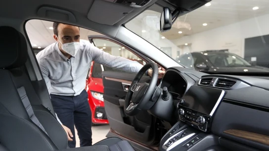 Un hombre con mascarilla observa un coche Un hombre con mascarilla observa un coche