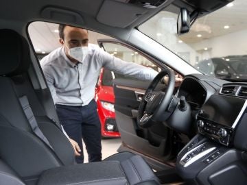 Un hombre con mascarilla observa un coche