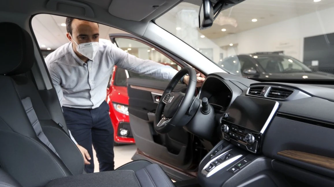 Un hombre con mascarilla observa un coche