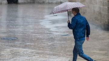 Una persona se protege de la lluvia con paraguas en el centro de Valencia
