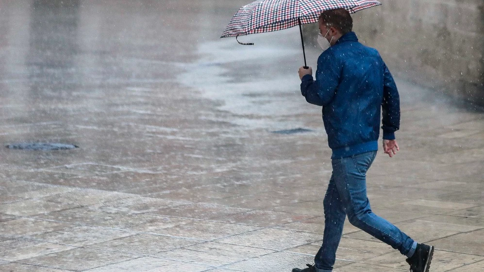 Una persona se protege de la lluvia con paraguas en el centro de Valencia