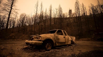 Un vehículo quemado se encuentra junto a una gasolinera en el Bosque Nacional Sierra, California