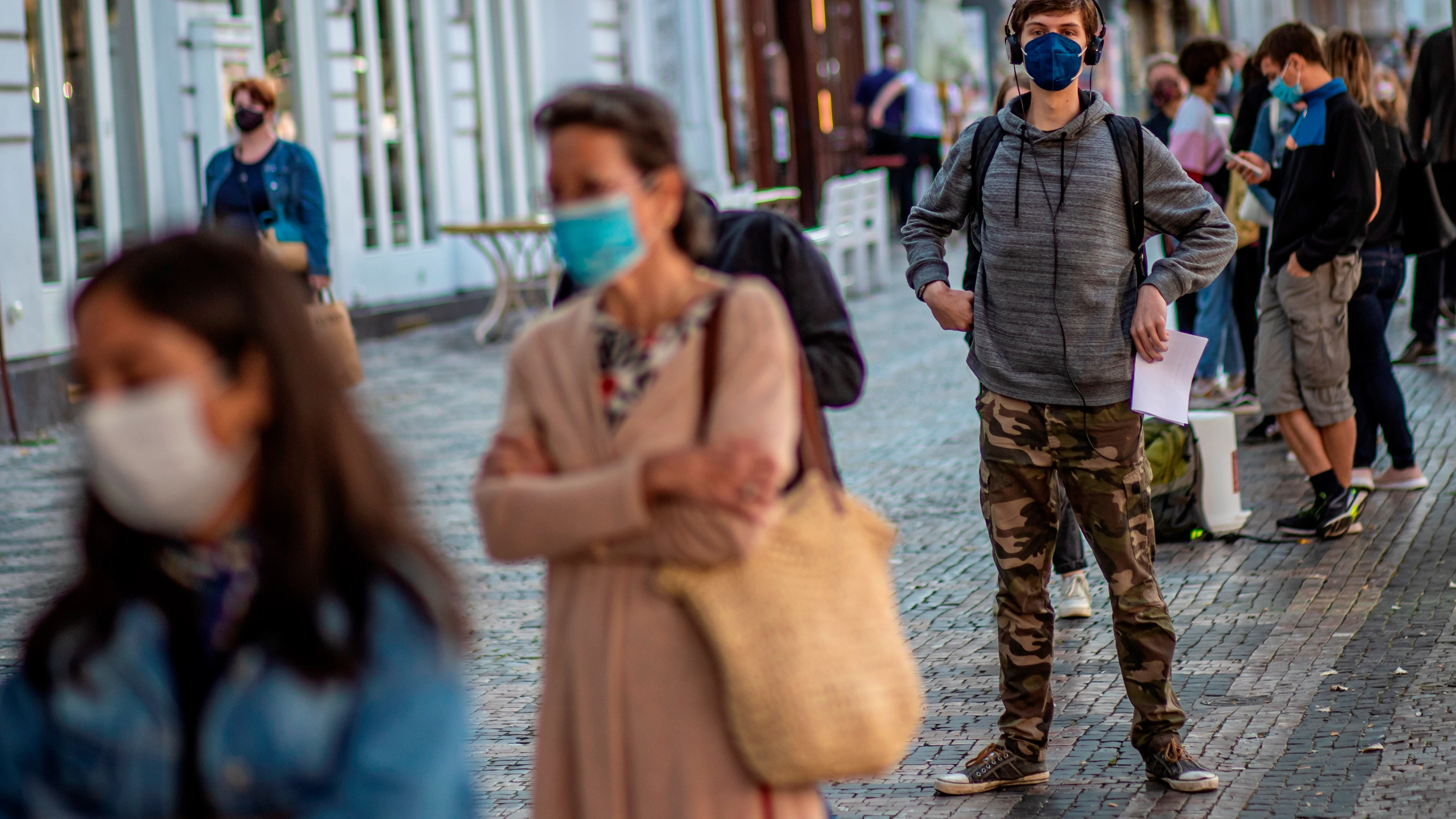 Una cola de gente con mascarillas en una calle de Italia