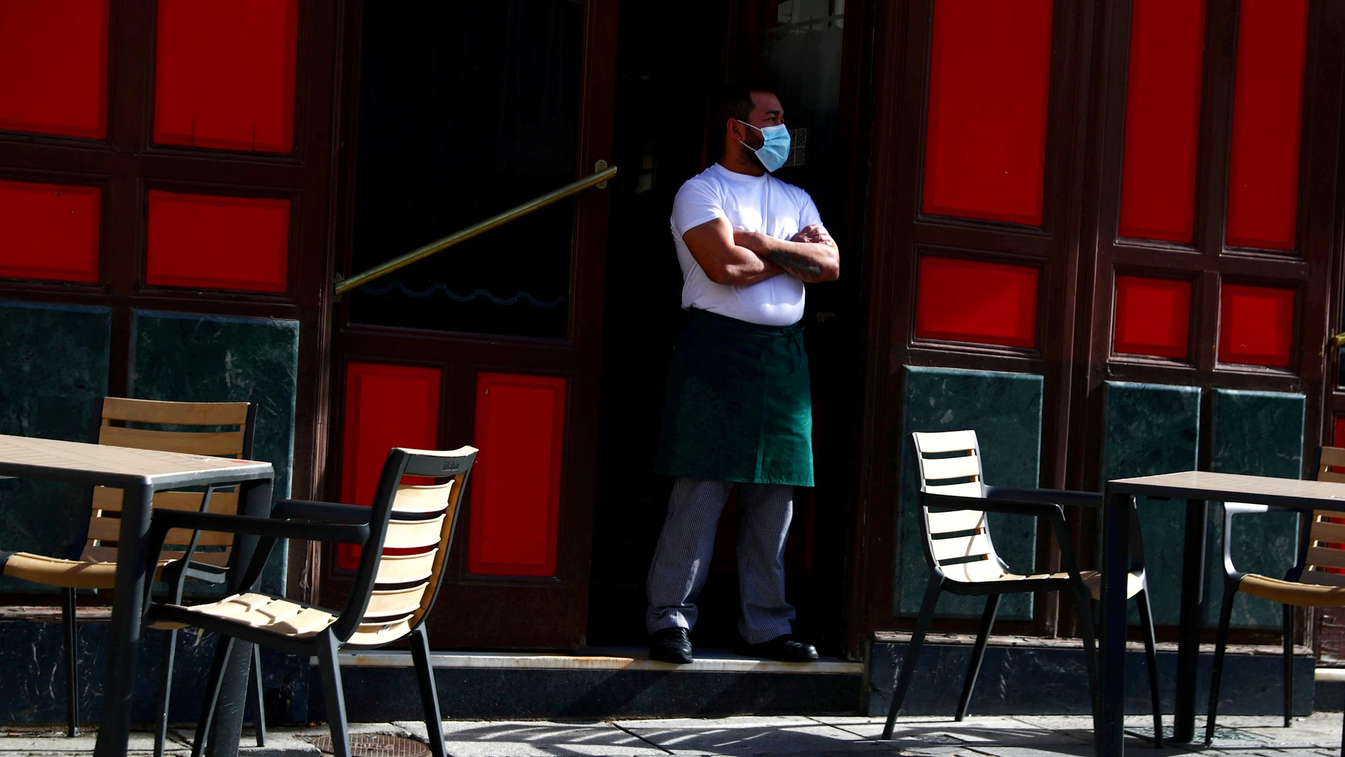 Un camarero con mascarilla espera a clientes en una terraza de Madrid
