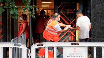 Un voluntario de la Cruz Roja atiende a un vecino del barrio del Remei de Vic (Barcelona).