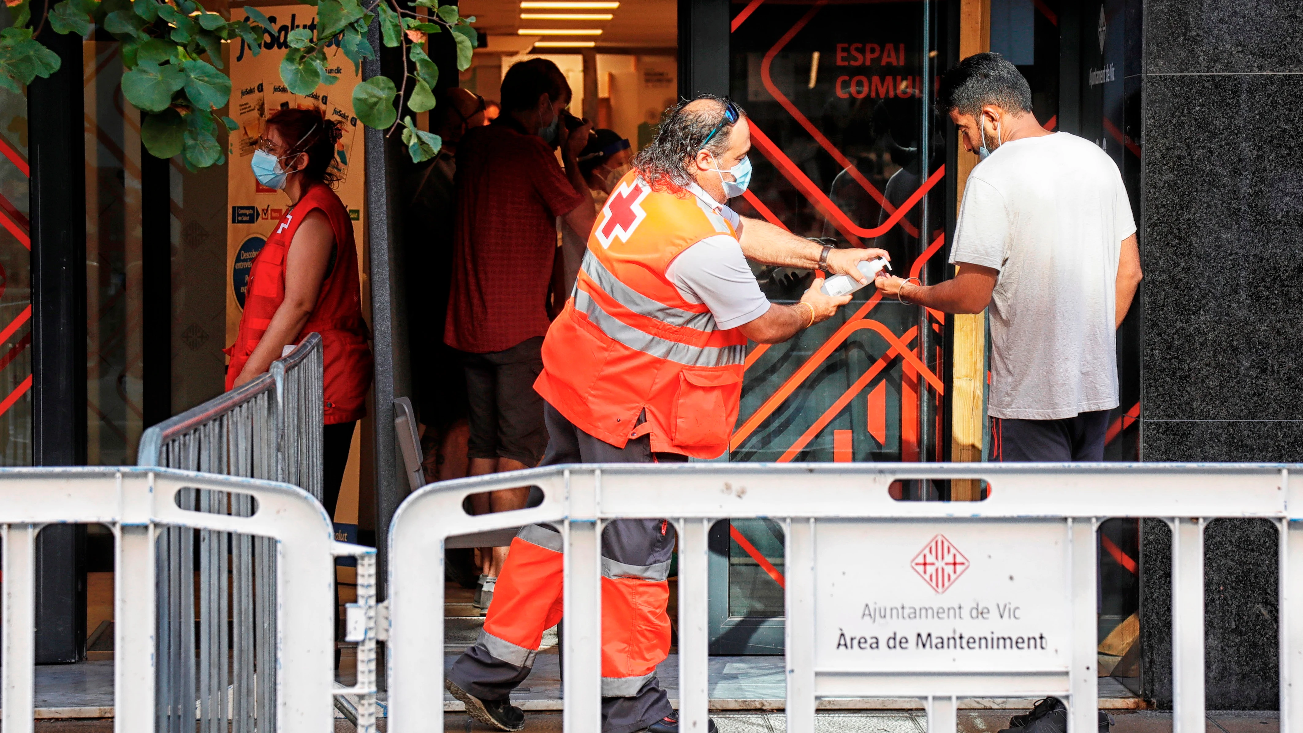 Un voluntario de la Cruz Roja atiende a un vecino del barrio del Remei de Vic (Barcelona).