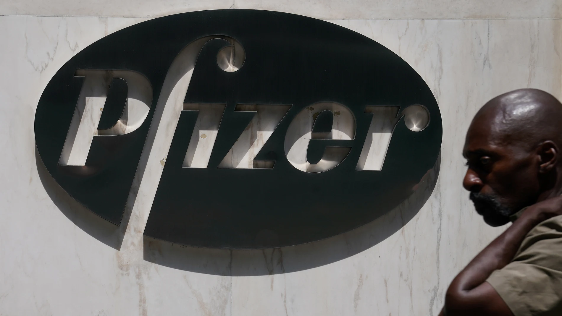 Un hombre camina frente a la sede de Pfizer