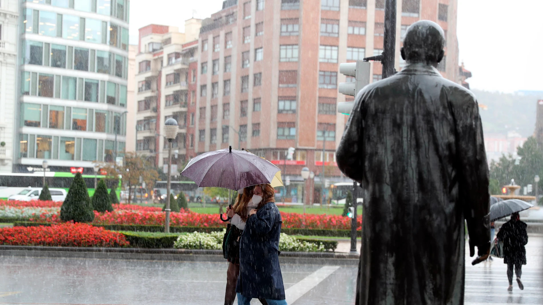 Varias personas se protegen de la fuerte lluvia en Bilbao
