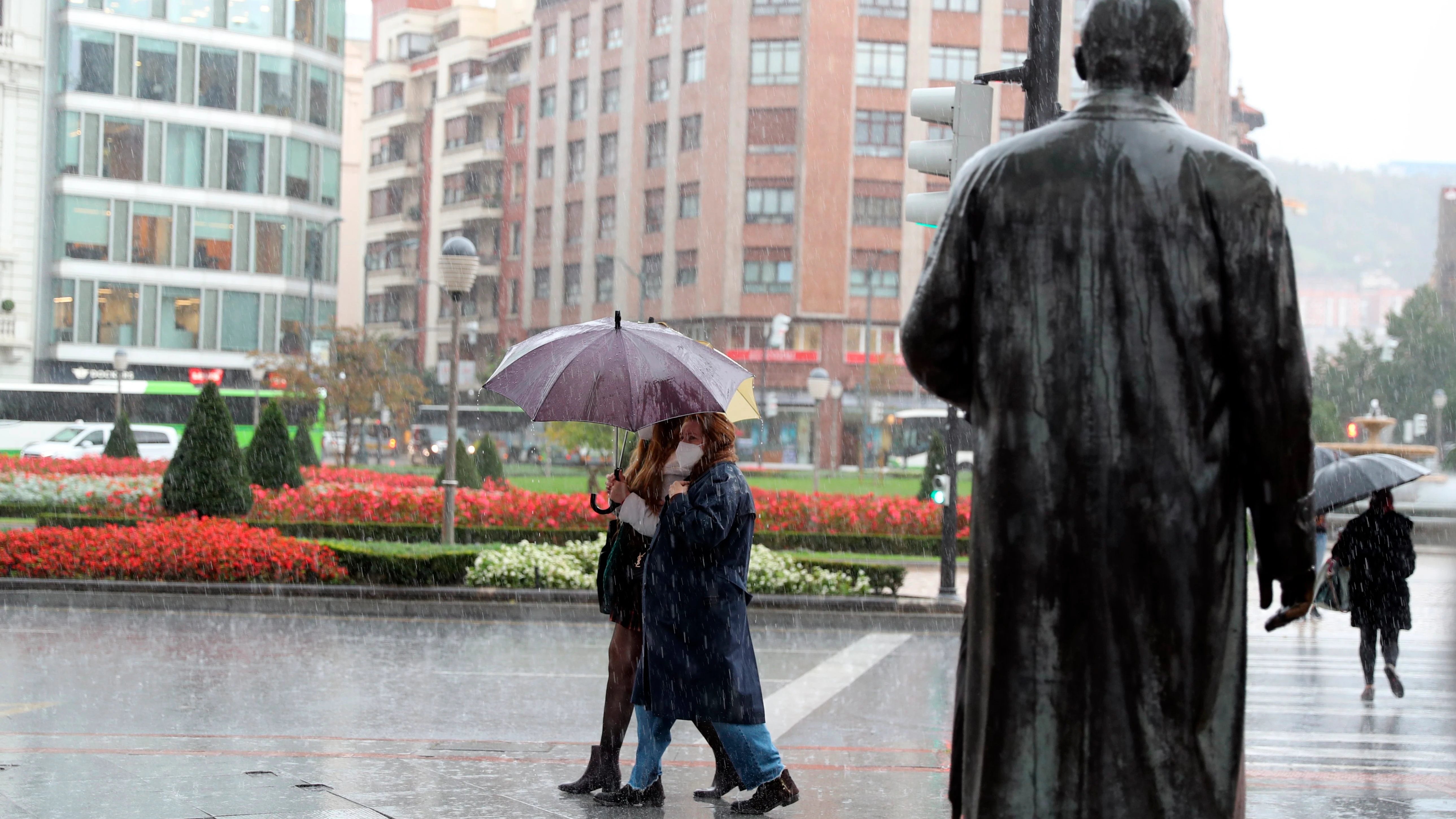 Varias personas se protegen de la fuerte lluvia en Bilbao