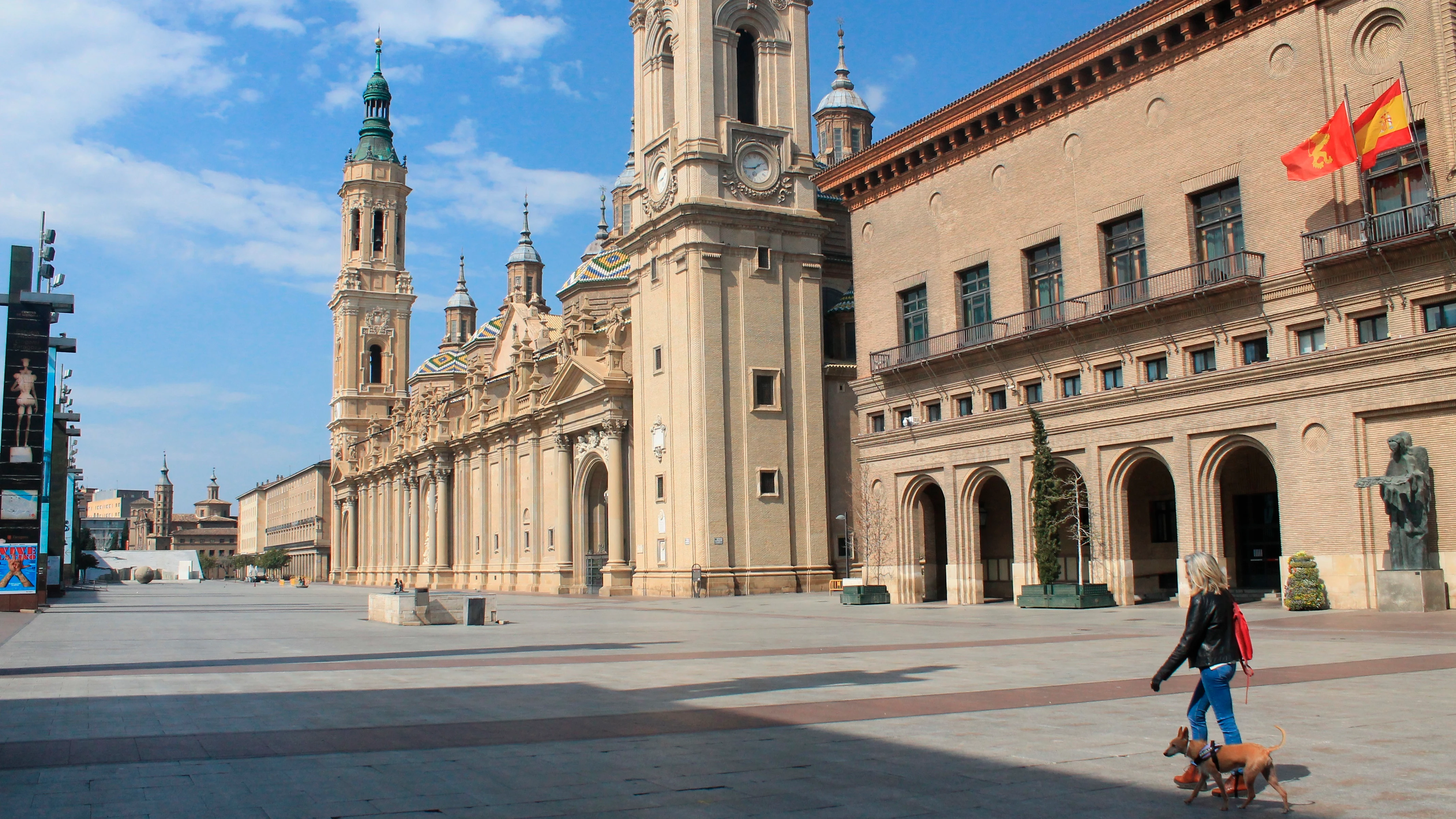 Una mujer pasea a su perro en la plaza del Pilar en Zaragoza