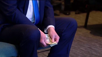Donald Trump contando varios billetes antes de hacer una donación