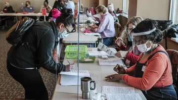 Una votante firma para recibir su papel de voto en Wisconsin.