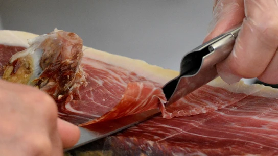 Imagen de archivo de una persona cortando jamón. Imagen de archivo de una persona cortando jamón.