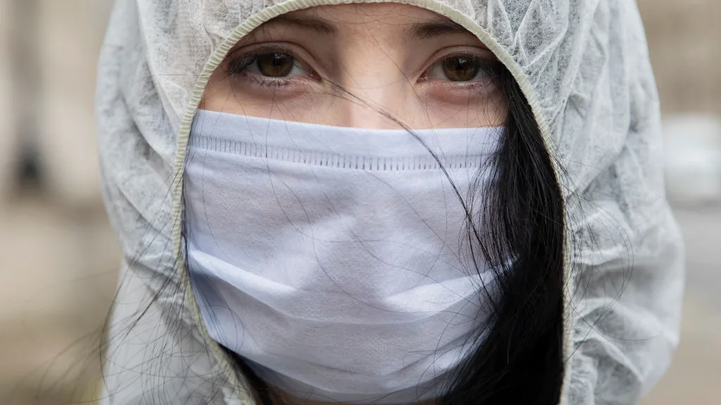 Una mujer con mascarilla mira a cámara