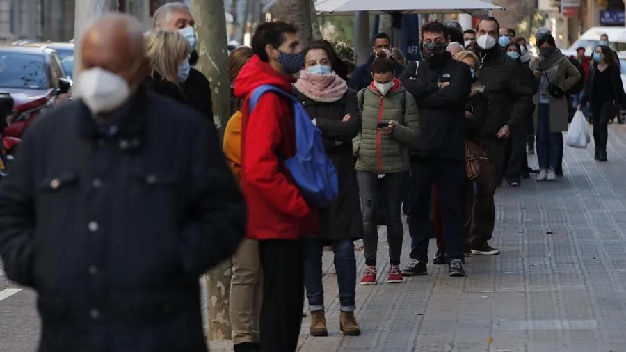 Numerosas personas hacen cola para hacerse test de antígenos en un laboratorio privado de Barcelona.